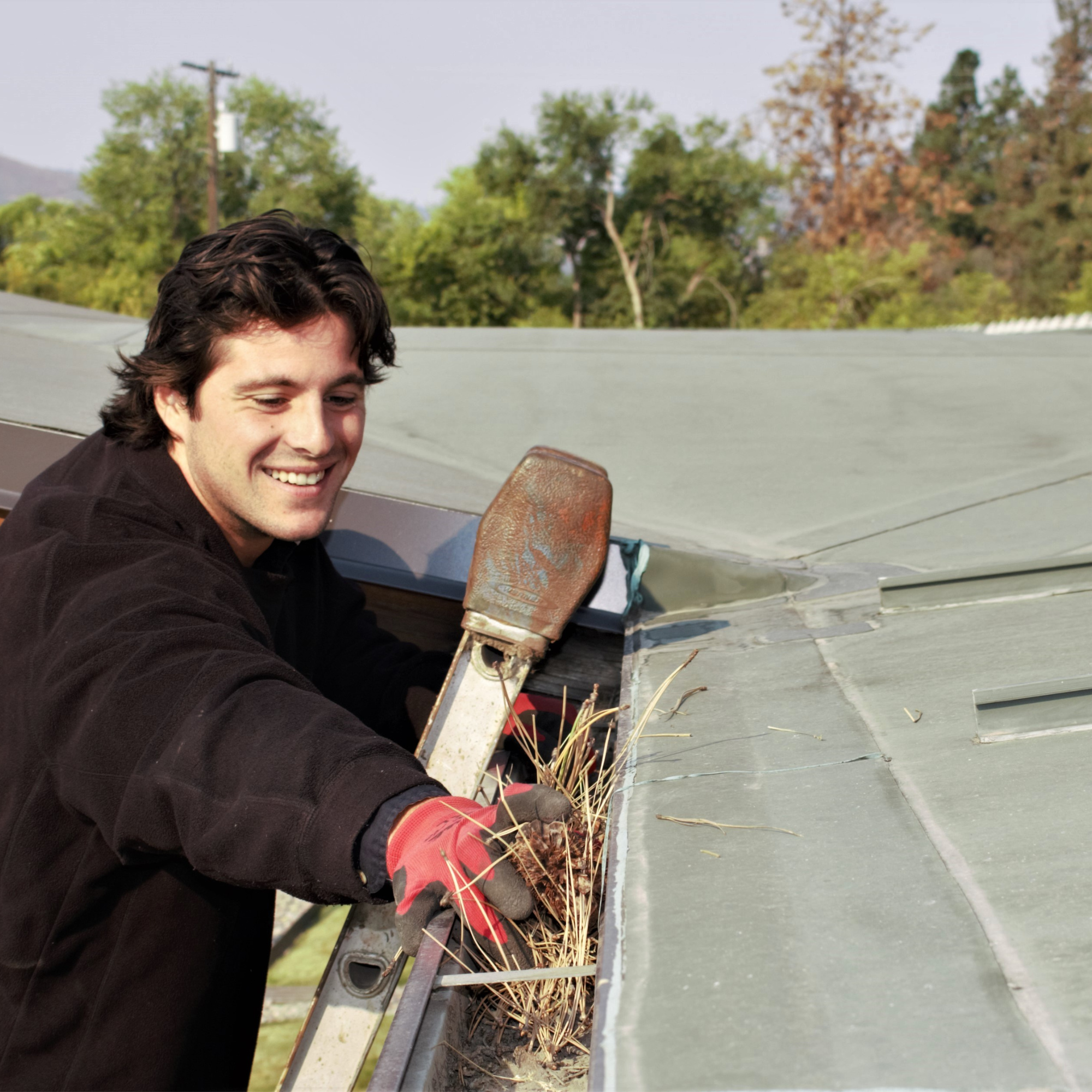 Person cleaning gutters on a sunny day 